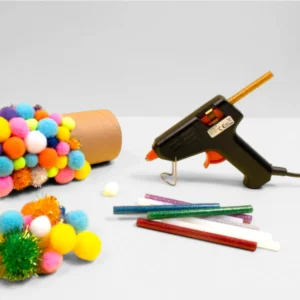 Limpistol med glitterlimstavar och färgglada pompoms, redo för ett pysselprojekt.