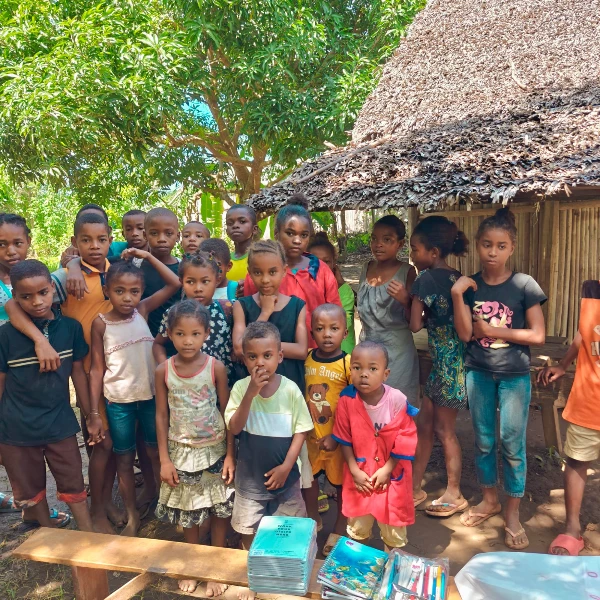 Barnen i utsatt skola Grupp barn framför sin byskola i Madagaskar med nytt skolmaterial