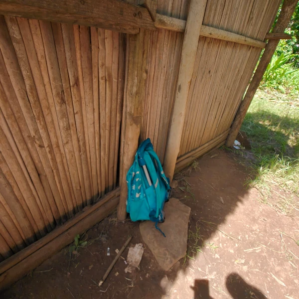 Ryggsäck till elev i skolan Blå ryggsäck lutad mot väggen i ett enkelt klassrum i Madagaskar